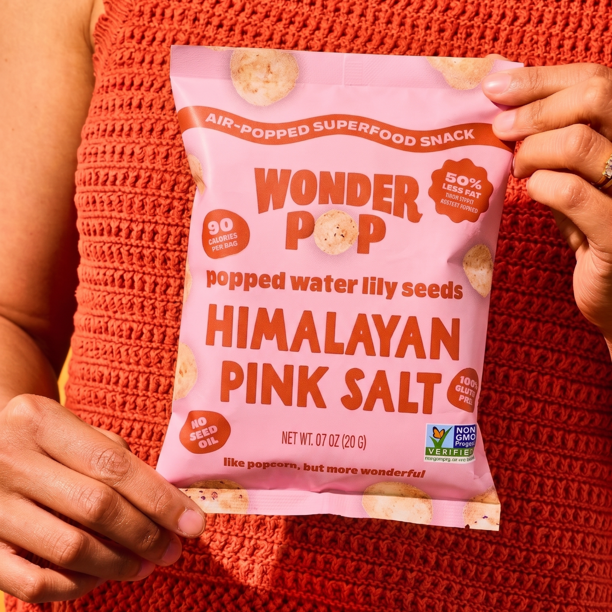 Person holding a pink package of Wonder Pop Himalayan Pink Salt snack.