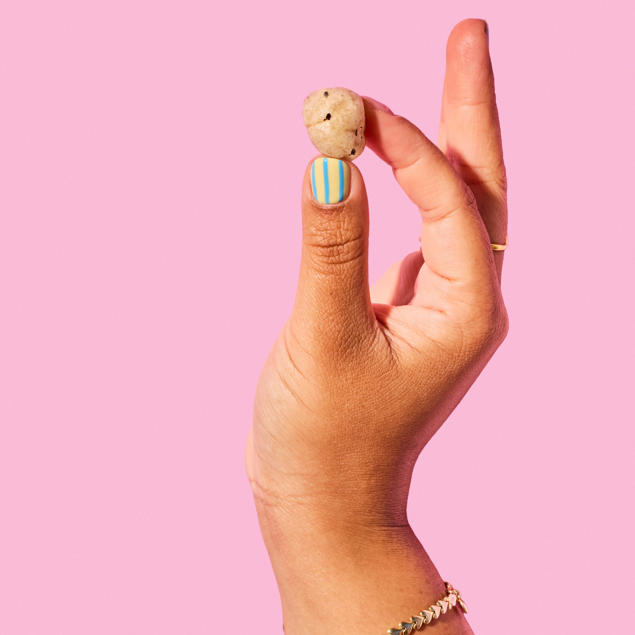 Hand holding a small pop against a pink background